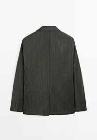 Giacca grigia con texture a spina di pesce, ampio revers a lancia, maniche lunghe e una spacco singolo sul retro. Dettaglio con bottoni sui polsini delle maniche.