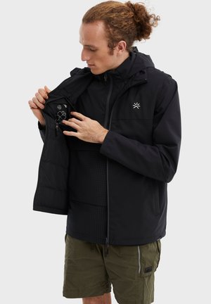 Veste noire avec une fermeture éclair à l'avant, une capuche et une poche intérieure avec des icônes. Le matériau texturé contraste avec le tissu lisse.