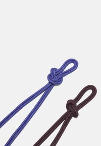 Due pizzi decorativi: uno di un blu brillante con un motivo testurizzato, l'altro di un rosso scuro con un discreto pattern a scacchi neri. Entrambi presentano nodi a spirale.