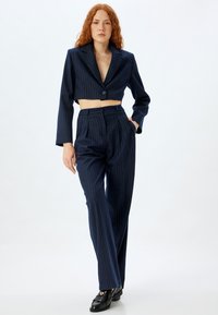 Marineblauwe gestreepte cropped blazer met een enkele knoopsluiting, gecombineerd met op maat gemaakte hoge taille broeken met een rechte pijp en zakken.