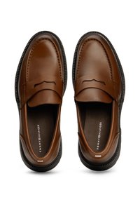 Braune Lederloafers mit glatter Oberflächenstruktur, ausgestattet mit einem dekorativen Riemen, gesteppten Details und schwarzem Gummisohle.