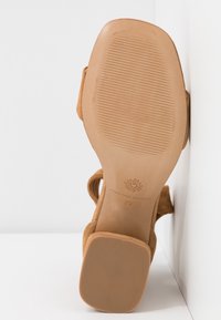 Sandale en daim beige avec bout carré, talon bloc et semelle texturée, taille 37, vue de dessous.