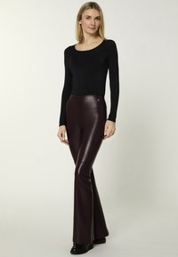 Burgundy faux leather flared pants with a smooth finish, paired with a fitted black long-sleeve top. No visible patterns or hardware.