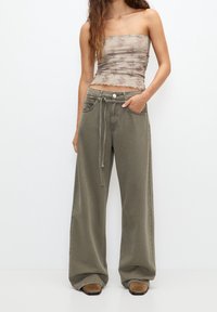 Pantalon kaki à jambes larges avec taille à cordon, associé à un top bustier à imprimé floral. Tissu lisse, coupe décontractée et grandes poches.