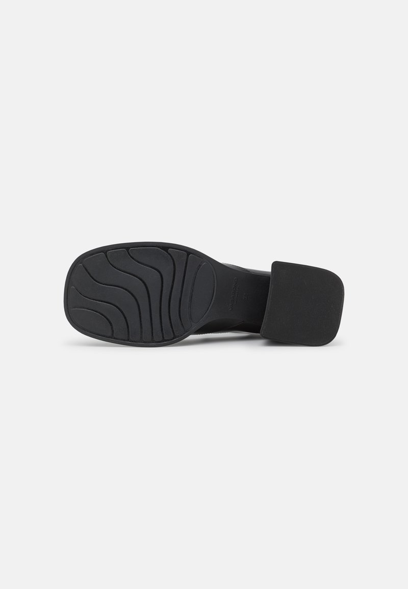 Chaussure à talon noir avec un large talon plat. La semelle présente un motif ondulé pour une meilleure adhérence, avec une surface supérieure lisse en matériau texturé.