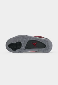 Σόλα γκρι και μαύρου αθλητικού παπουτσιού Air Jordan με κόκκινο λογότυπο Jumpman και λεπτομερή σχέδια πέλματος σε λευκό φόντο.
