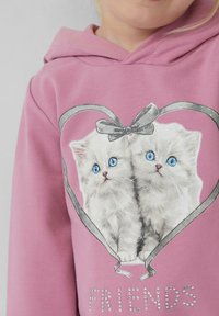 Lichtroze hoodie met een hartvormig ontwerp met twee geïllustreerde kittens, grijze lintaccenten en het woord "VRIENDEN" in rhinestones.