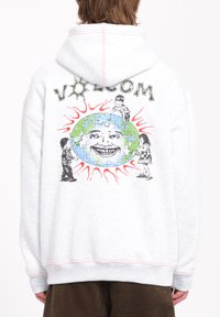 Lichtgrijze hoodie met een grote grafische print op de achterkant, featuring een lachend gezicht, kinderen en een puzzelvormige aarde, afgewerkt met rood.