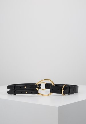 Zwart leren riem met dubbele banden en een gouden metalen ovale gesp en lus, weergegeven op een witte ondergrond tegen een grijze achtergrond.