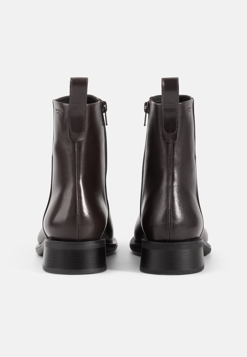 Brown leather ankle boots with a glossy finish, side zippers, and looped pull tabs; flat soles with a slightly elevated heel.