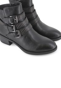 Botas negras hasta el tobillo hechas de cuero suave con tres correas ajustables que presentan acentos de tachuelas y un tacón bajo.