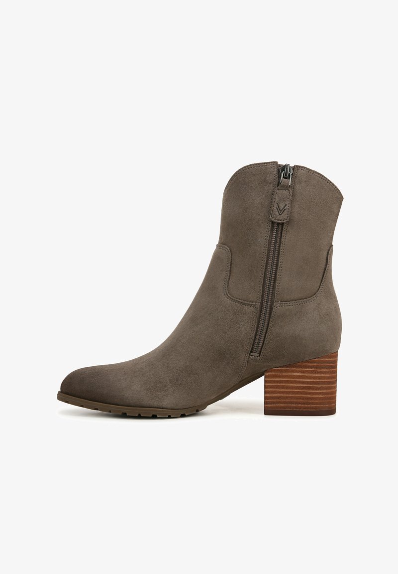 Bottine en daim gris avec un bout pointu, fermeture éclair sur le côté et un talon empilé en bois. Surface texturée et semelle en caoutchouc durable.