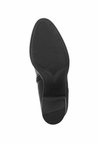 Suela de zapato de cuero negro con un patrón texturizado, presentando una forma cónica y un borde suave. La sección del tacón muestra detalles mínimos.