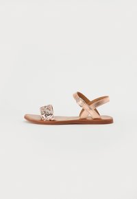 Rosen-gull flate sandaler med en glitrende stropp og justerbar ankelspenne. Glatt tekstur med et enkelt, åpent design. Flat såle.