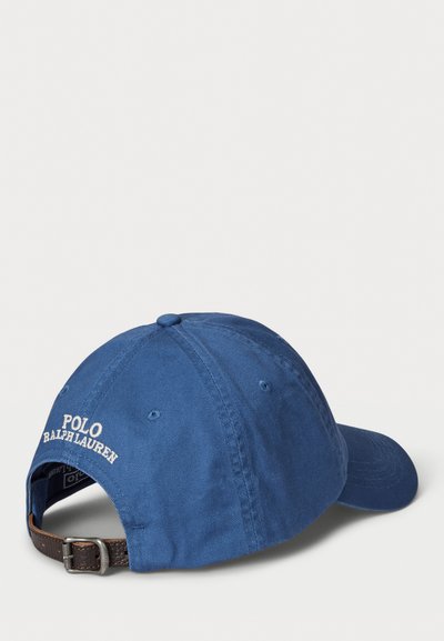 Modra bombažna kapica za bejzbol z ukrivljenim vizirjem, nastavljivim rjavim usnjenim trakom in belim vezenim logotipom "POLO RALPH LAUREN" zadaj.