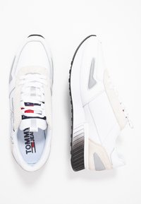 Białe sneakersy wykonane z kombinacji gładkiej skóry i zamszu, z szarymi akcentami, teksturowaną podeszwą i wielokolorowymi detalami z logo.