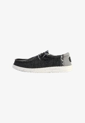 Szare materiałowe buty typu slip-on z zaokrąglonym noskiem, z białą nakrapianą podeszwą i wzorzystymi akcentami na pięcie.
