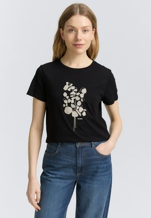 T-shirt noir à manches courtes avec un motif floral abstrait crème. Matière en coton doux avec une coupe décontractée et un col rond.