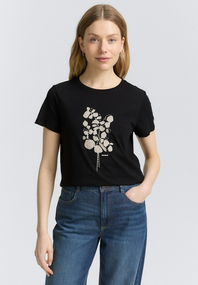 Svart t-shirt med kort ärm som har en krämfärgad abstrakt blommig grafisk design. Mjuk bomullsblandning med avslappnad passform och rundad halsringning.