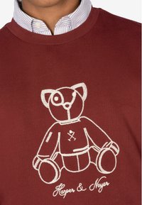 Bordeauxfarbenes Sweatshirt mit einem weißen gestickten Bärenmotiv. Gerippter Kragen und strukturierter Stoff mit dem Text "Harper & Neyer" unter dem Bären.