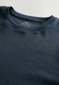 Tamnoplava majica s okruglim izrezom, izrađena od glatkog pamuka. Ima regularni kroj s etiketom koja prikazuje marku i podatke o porijeklu.