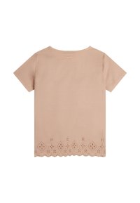 Camiseta de manga corta color beige claro con un dobladillo festoneado y un patrón de corte en forma de flor a lo largo del borde inferior. Tela suave y lisa.