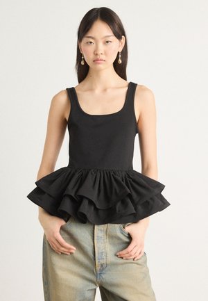 Black sleeveless top with a square neckline and layered ruffled hem, paired with light-wash jeans. Smooth fabric with a matte finish.
