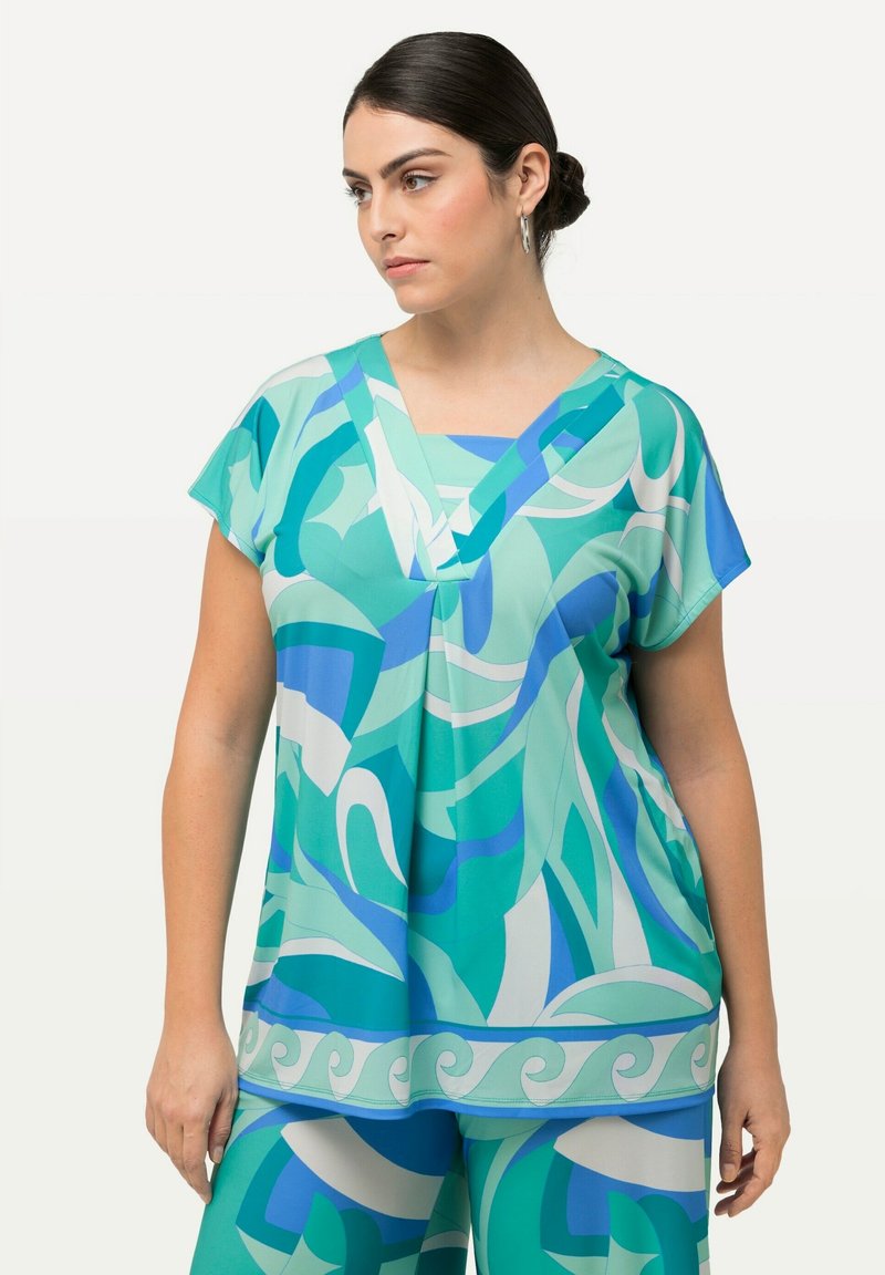 Top de manga corta y cuello en V en tonos de azul y verde con patrones abstractos de olas, hecho de tela suave y con un corte holgado.