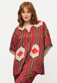 Rot- und braun gemusterte Kurzarmbluse mit geometrischen Designs in Creme und Orange. Weicher Stoff mit legere Passform.