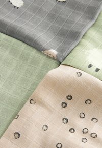 Vier Stoffmuster präsentiert: grau mit Schafmuster, hellgrün mit Rautenmuster und beige mit ovalen Punkten, alle mit einem Rautendesign.