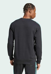 Sort sweatshirt med blå kantstriber på skuldrene, rund hals, ribbede manchetter og kant, tekstureret stof, afslappet pasform.