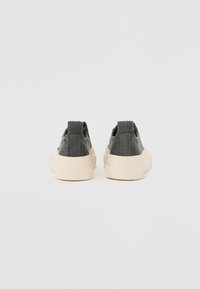 Leinenschuhe mit einem dunkelgrauen Obermaterial, kontrastierender beigefarbener Gummisohle und flachem Absatz. Verfügt über strukturierte Akzente und elastische Seitenpaneele.