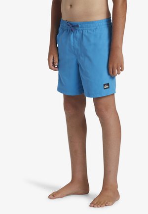Bañadores azules hechos de tela ligera, con una cintura elástica con cordón y un pequeño parche con el logo en el lado.