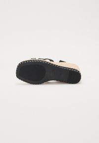 Sandales à bride noire avec un dessus en fibres naturelles tissées et une semelle en caoutchouc noir. Couture décorative le long du bord. Design plat. Taille 37.