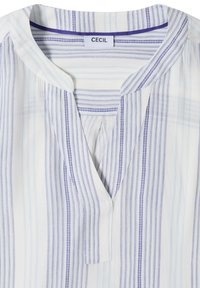 Chemise blanche à rayures verticales bleues et bleu clair, col en V, avec une étiquette de marque "CECIL" à l'intérieur du col.