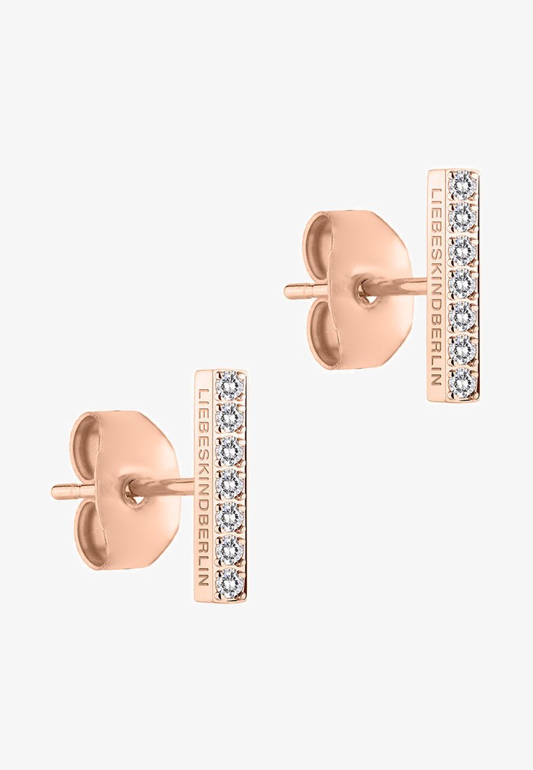 Boucles d'oreilles en or rose, présentant un design en barre verticale avec six cristaux transparents et un nom de marque gravé sur le côté.