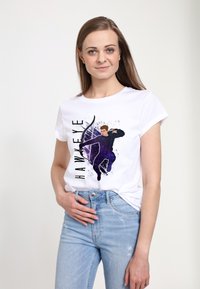 Bílý bavlněný tričko s grafickým potiskem postavy se lukem a šípem na fialovém pozadí s rozstřikem, označené "HAWKEYE."