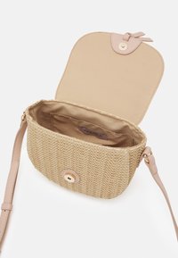 Borsa a tracolla in paglia intrecciata di colore beige con patta in pelle liscia e chiusura a scatto dorata. L'interno è foderato in morbido tessuto con etichetta.