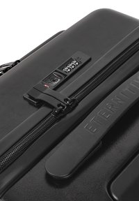 Black hard-shell suitcase with a combination lock, textured finish, engraved "ETERNITY" branding, and smooth zipper hardware.