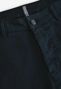 Pantaloni navy scuri realizzati in tessuto leggero. Caratterizzati da una chiusura a bottone e un accento in tessuto a righe nella vita. Tessuto morbido.