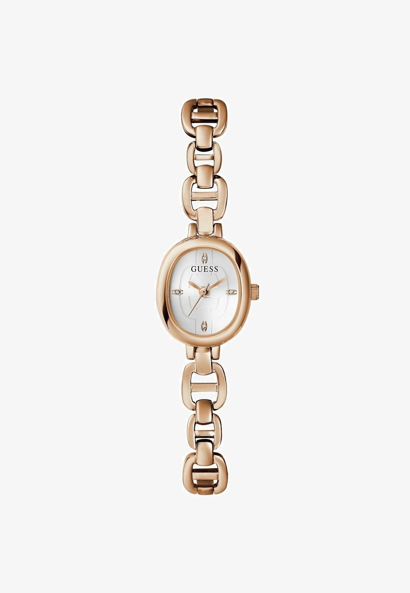 El reloj de pulsera de color dorado tiene una cara ovalada con una esfera blanca, el logo "GUESS" y acentos de piedras en los marcadores de horas. Diseño de correa de eslabones.