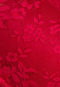 Röd spetstyg med blommönster, en texturerad yta och en lätt lyster, vilket skapar ett rikt och intrikat utseende.