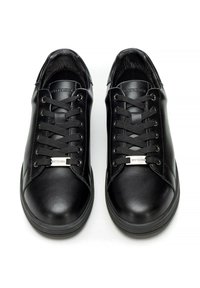 Sneakers in pelle nera con una superficie liscia, punta rotonda, design con lacci e accenti metallici ai lati. Suole in gomma piatte.