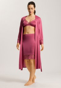 Mauve-lingeriesetti, joka sisältää satiinisen kylpytakin, jossa on pitsikoristeita, saumatonta rintsikkasettiä ja lyhyen hameen, jonka helmassa on pitsireuna.