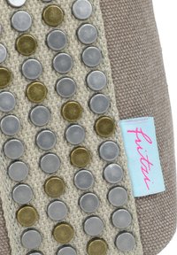 Borsa in tessuto marrone chiaro con una texture, decorata con borchie metalliche in argento e oro disposte in righe. Presenta un'etichetta azzurra chiaro con la scritta "fritzi" in rosa.