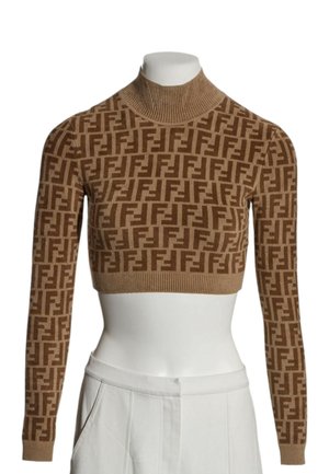 Brązowy krótki sweter z golfem z powtarzającym się ciemnobrązowym geometrycznym wzorem oraz długimi rękawami na białym torsie manekina.