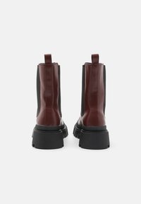 Bordeaux ankelstøvler med en blank finish; elastiske sidepaneler; robust sort gummisål; trækflapper for nem påtagning.