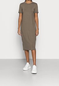 Khaki sukienka z krótkim rękawem, okrągłym dekoltem, sięgająca do połowy łydki, o gładkiej fakturze, zestawiona z białymi trampkami. Minimalistyczny design.