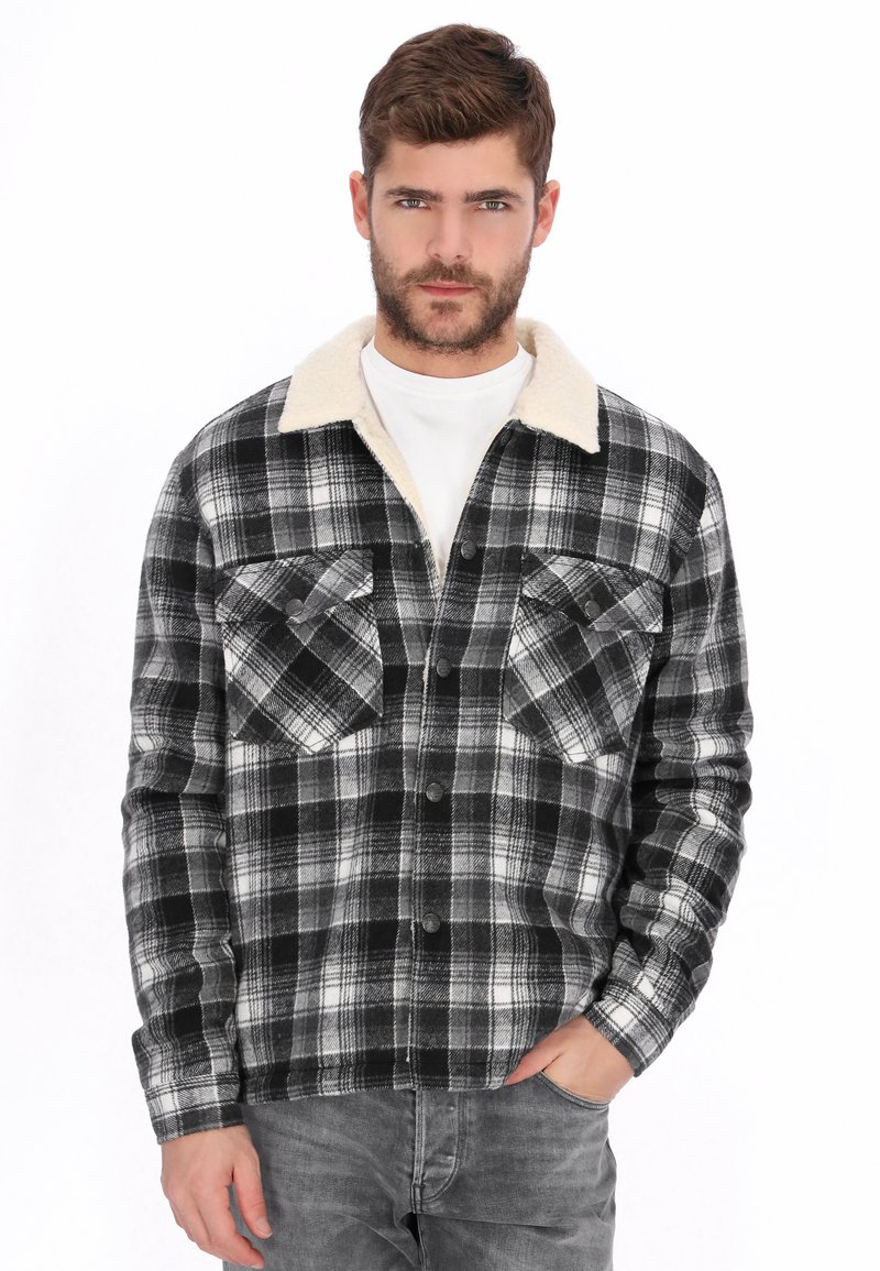 Camisa de franela a cuadros en blanco y negro con forro de cuello color crema, con dos bolsillos delanteros y cierres de botones.