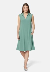 Ärmelloses mintgrünes Kleid mit einem kragenlosen Ausschnitt, fließendem A-Linien-Design, seitlichen Taschen und einem glatten, strukturierten Stoff.